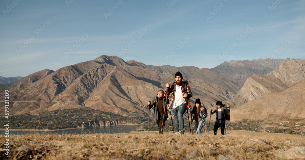 Group of four hipster friends travelling together, hiking and adventuring in mountains. Students on vacation - friendship, travel destination concept 