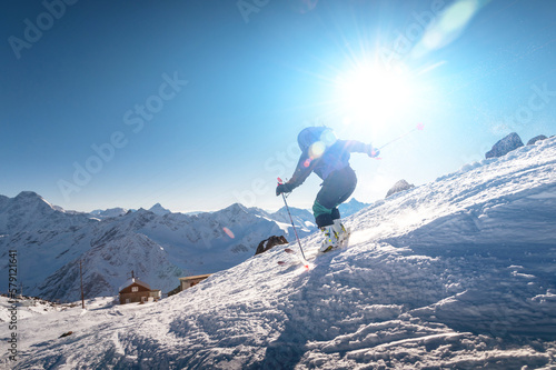 young female skier quickly descends the slope in the alpine mountains. Winter sports and recreation, active recreation © yanik88