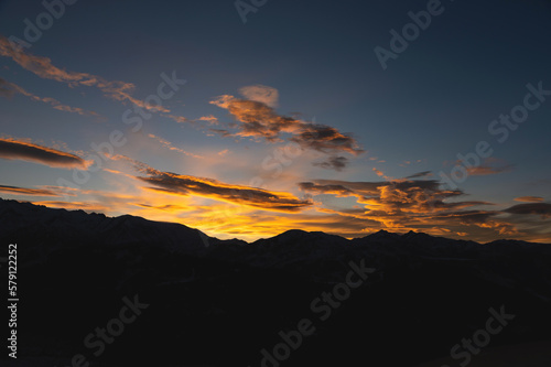 Colorful sunset over mountain hills. The black silhouette of the mountains is visible through the picturesque glow