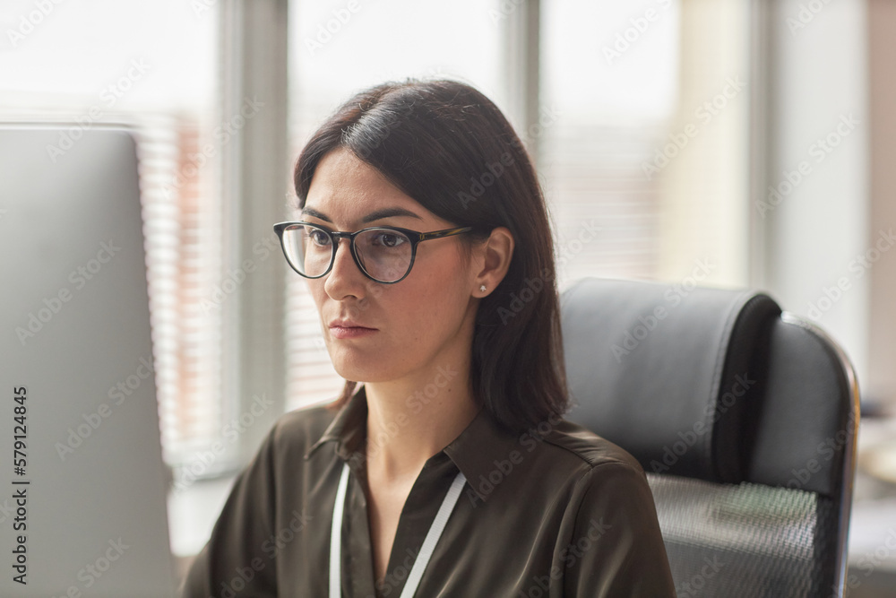 Portrait of focused businesswoman wearing glasses using computer at workplace Portrait of focused businesswoman wearing glasses using computer at workplace