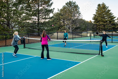 Four Female Pickleball Players Volley near the Net