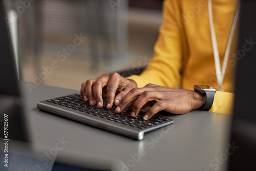 Close up of male hands typing at keyboard while using computer in high tech office, copy space