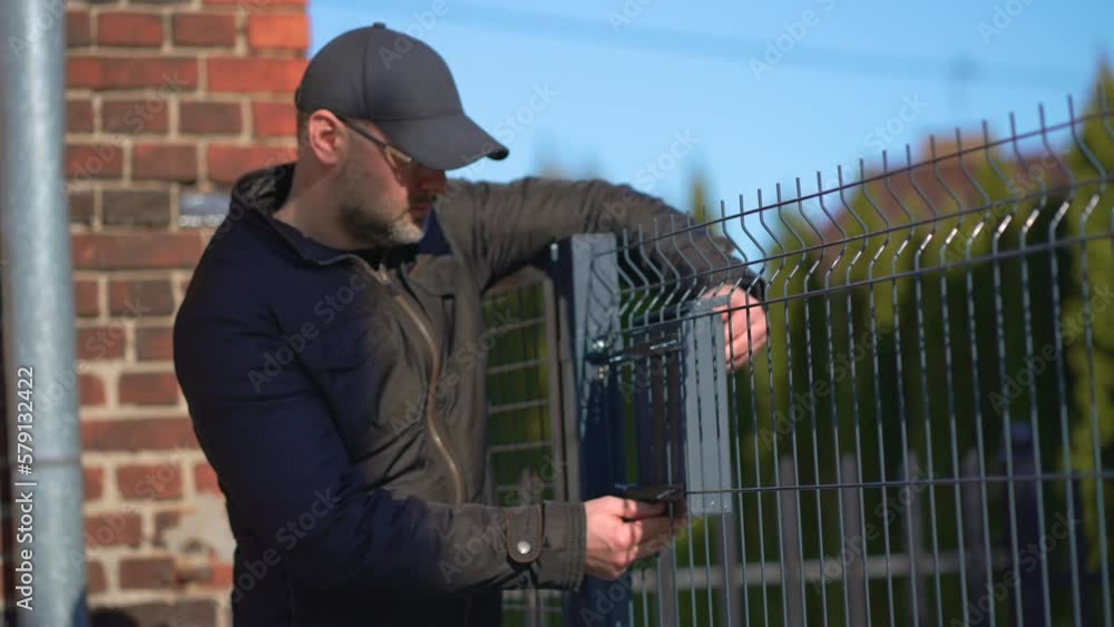 Repair of post box. Repairman repairing mailbox outdoor. Man in casual clothes working in house yard, handmade work concept Repair of post box. Repairman repairing mailbox outdoor. Man in casual clothes working in house yard, handmade work concept