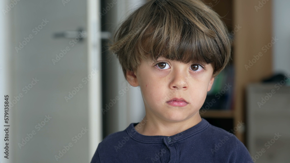 Portrait of one pensive young boy looking sideways thinking. Close up face of a child standing indoors with thoughtful expression Portrait of one pensive young boy looking sideways thinking. Close up face of a child standing indoors with thoughtful expression