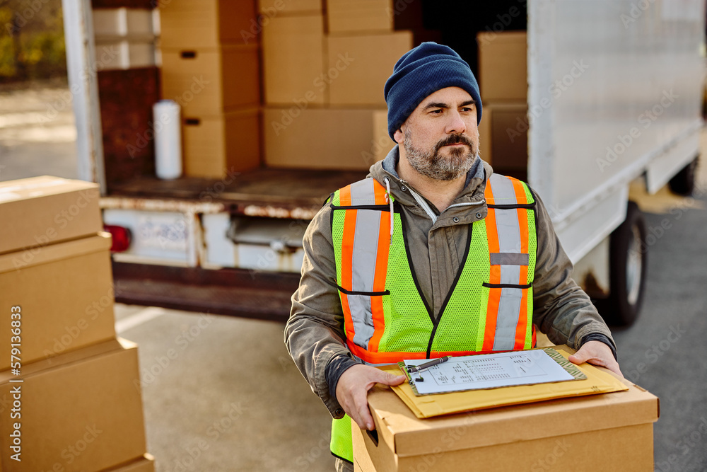 Mid adult delivery man unloading packages out of truck. Mid adult delivery man unloading packages out of truck.