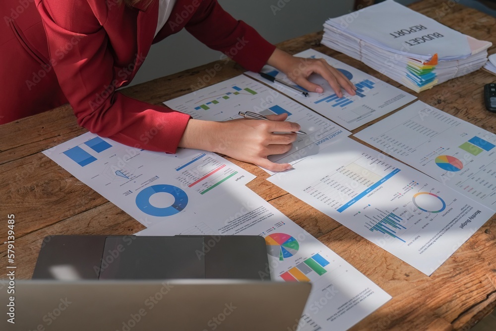 Closeup businesspeople working on finance document reading report paperwork spreadsheet using laptop at office desk Closeup businesspeople working on finance document reading report paperwork spreadsheet using laptop at office desk