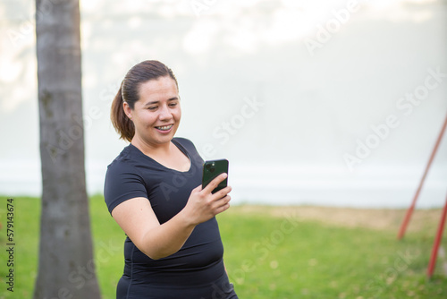 Sport woman in a park with black clothes and cellphone