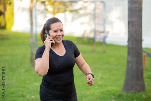 Sport woman in a park with black clothes and cellphone