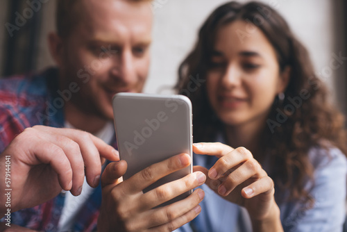 Blurred male and female bloggers using digital cellphone application for online chatting and messaging, selective frontage focus on modern smartphone technology for web social networking on leisure