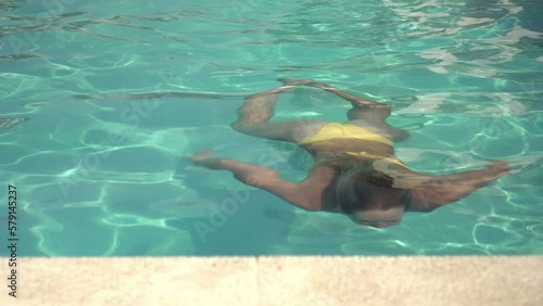 Attractive active woman swims underwater in an outdoor swimming pool