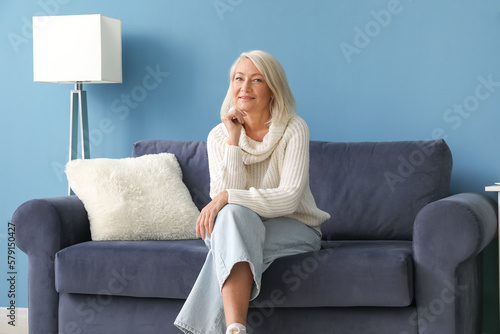 Mature woman sitting on blue sofa at home