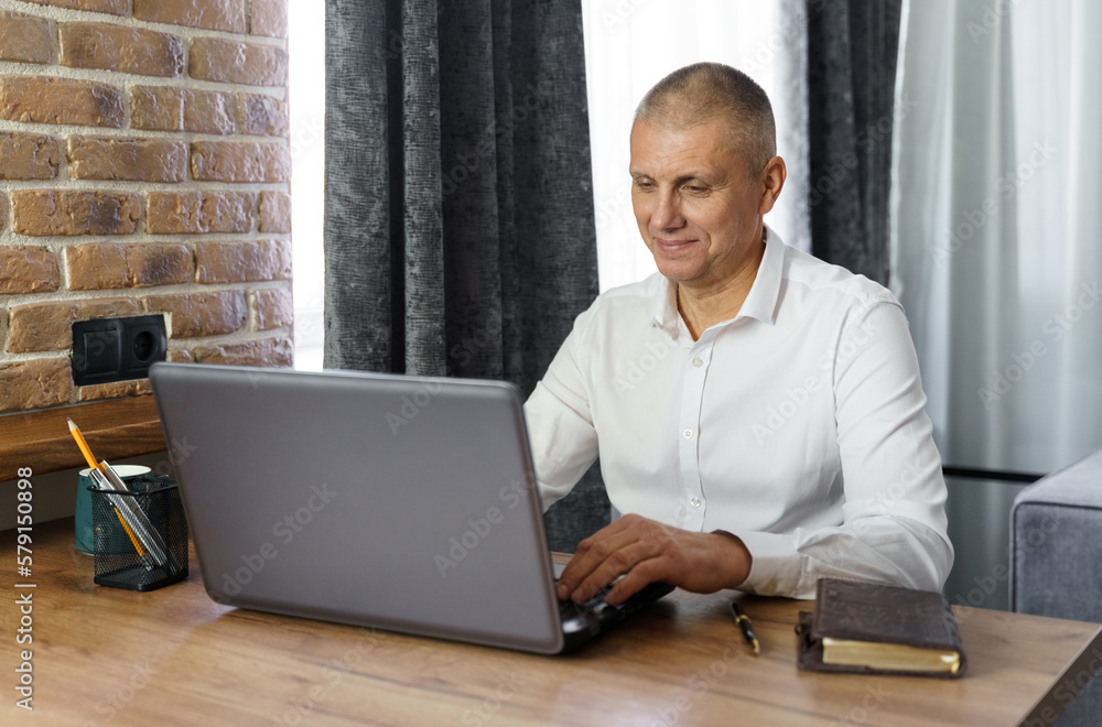 Fototapeta premium Business man, middle age, working at home with a laptop.
