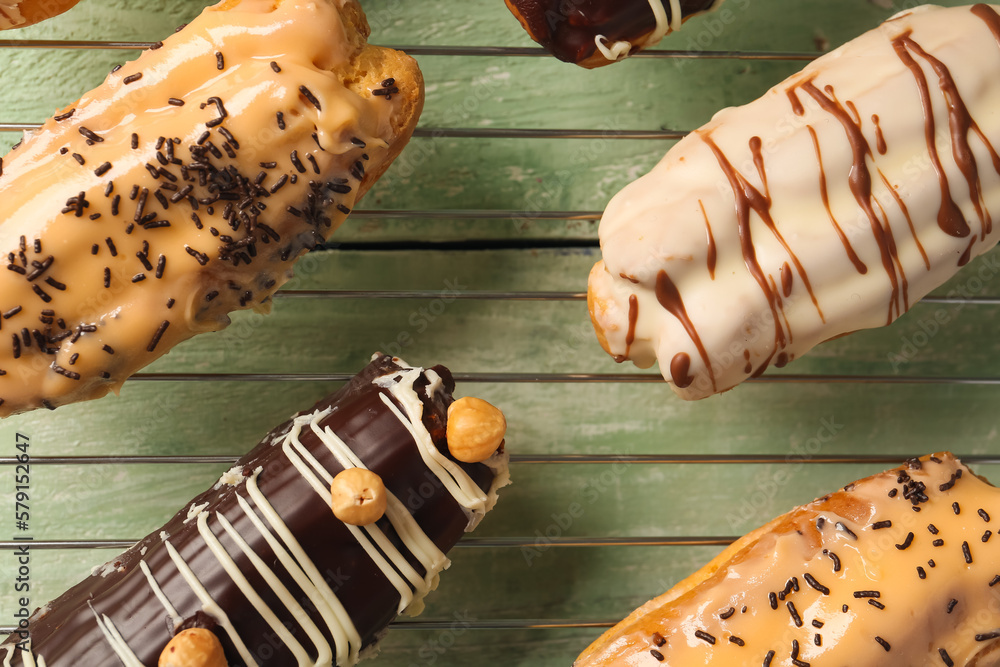 Grid with delicious eclairs on green wooden table Grid with delicious eclairs on green wooden table