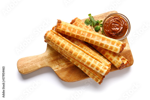 Board with delicious wafer rolls, boiled condensed milk and mint isolated on white background photo