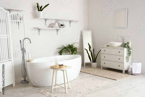 Interior of light bathroom with sink, bathtub and houseplants © Pixel-Shot
