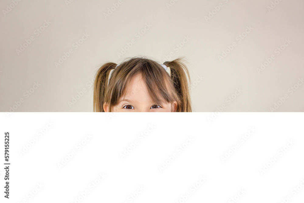 Portrait of a young happy girl smiling behind a white banner. Copy space. Portrait of a young happy girl smiling behind a white banner. Copy space.