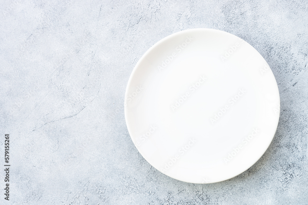 White plate at light stone table. Empty plate. Flat lay image. White plate at light stone table. Empty plate. Flat lay image.