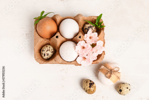 Easter eggs and sakura flowers on white wooden background