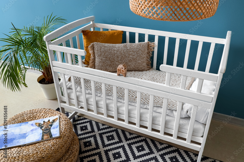Baby crib with pillows and wooden toys in bedroom - obrazy, fototapety, plakaty 