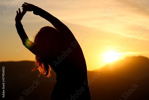 `mujer estirando mientras observa el amanecer