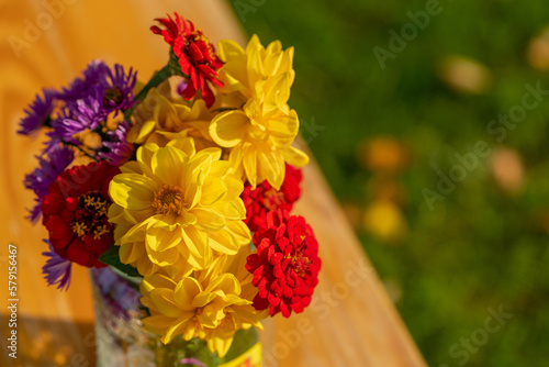 various colourful vibrant flower in glass jar on wooden table, flowers in vase in natural light