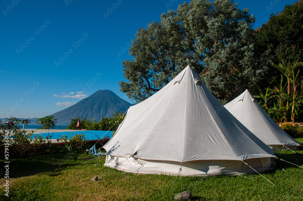 Two white tents in front of a lake and volcano on a sunny day in Guatemala
