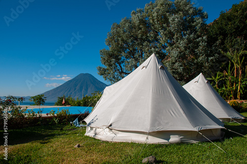 Two white tents in front of a lake and volcano on a sunny day in Guatemala © Matt