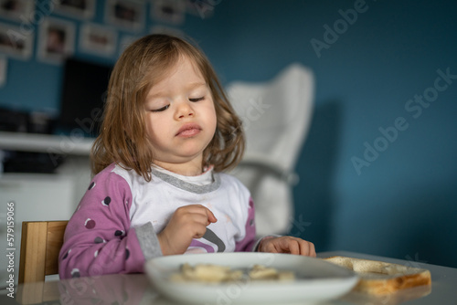 one girl small caucasian toddler female child eat at the table at home