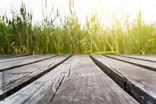 Wooden walkway on the lake with green grass and sunset background