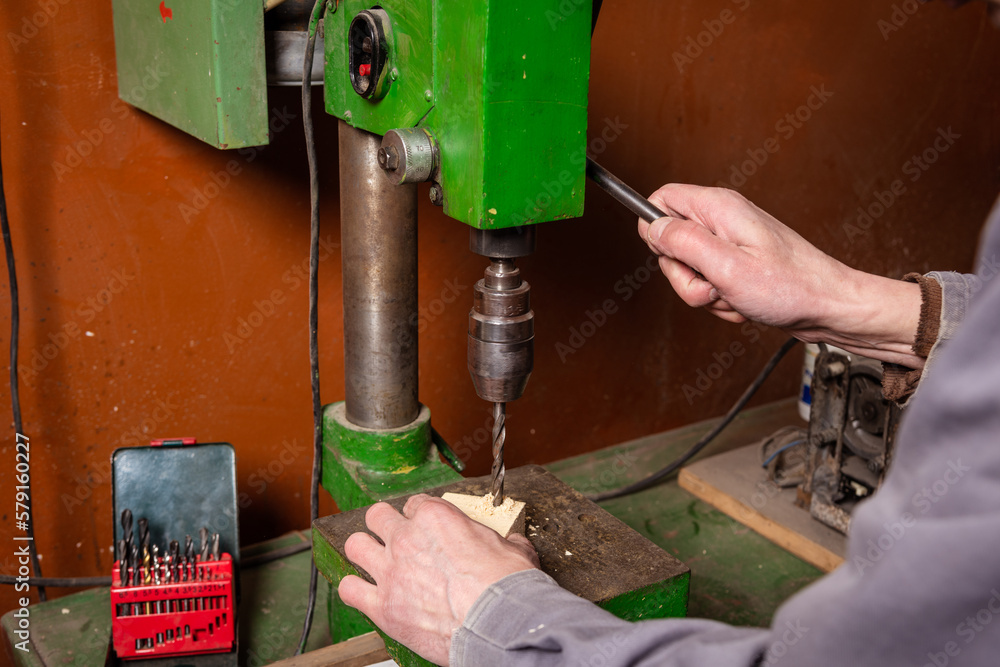 A carpenter works in a workshop with a saw, planer and various tools