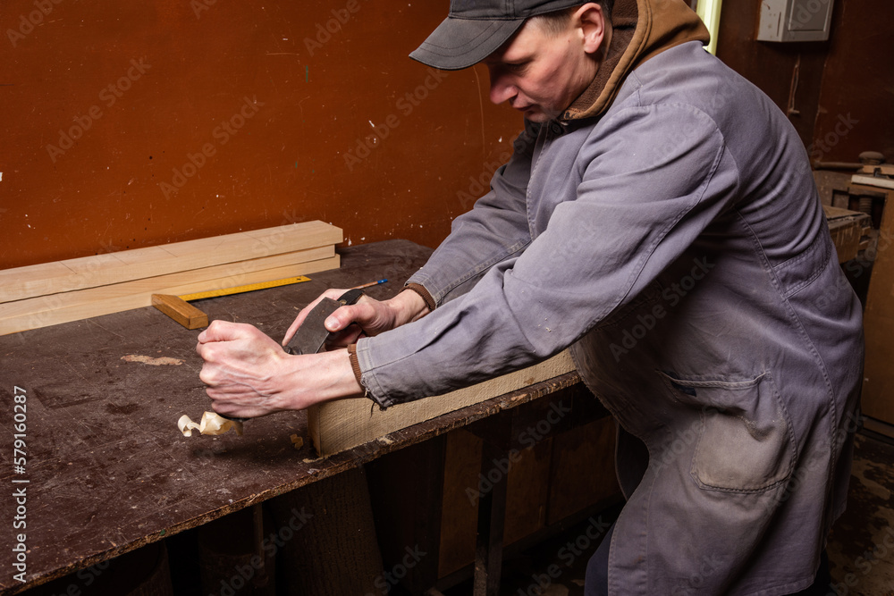 A carpenter works in a workshop with a saw, planer and various tools A carpenter works in a workshop with a saw, planer and various tools