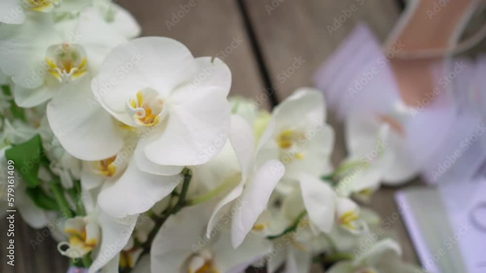 White bouquet of phalaenopsis orchid flowers. High-heeled shoes, sandals. Morning of the bride on the wedding day. Accessories details. White bouquet of phalaenopsis orchid flowers. High-heeled shoes, sandals. Morning of the bride on the wedding day. Accessories details.