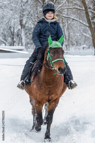 A girl rides a horse in the snow and frost of the cold north