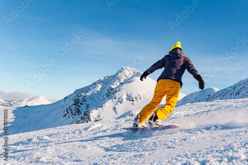 unrecognizable person in yellow clothes practicing snowboarding on a ski slope on a sunny day. winter and mountain sport concept.