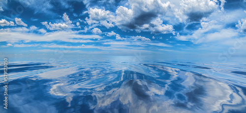 Cumulus clouds reflected on smooth, calm water
