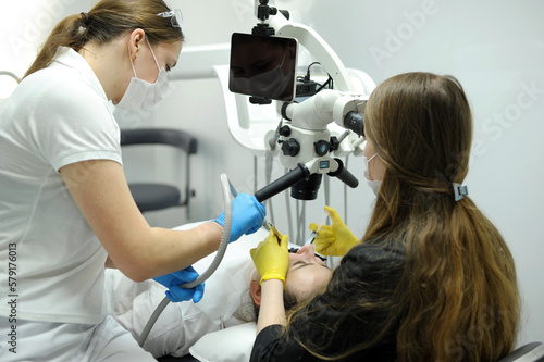 Modern dental equipment Medium shot of female dentist mask gloves using dental microscope to examine patients teeth doctor patient assistant dental treatment prosthetics canals fillings false teeth