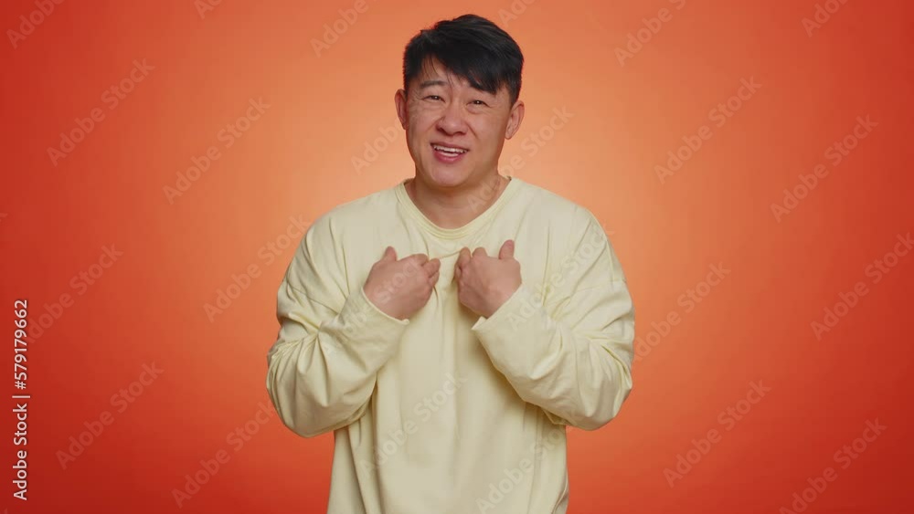 Give me money, please. Man rubbing fingers show cash gesture, demands to pay back the debt take loan, do shopping, begging, investment reward. Handsome chinese guy isolated on orange studio background Give me money, please. Man rubbing fingers show cash gesture, demands to pay back the debt take loan, do shopping, begging, investment reward. Handsome chinese guy isolated on orange studio background