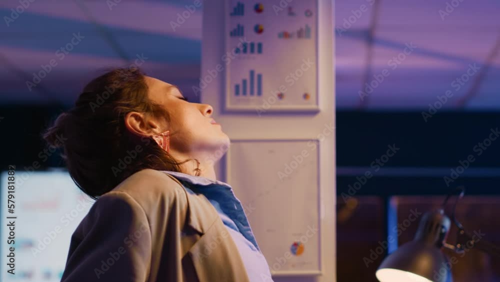 Stressed manager getting up and streching back, working late at night in business office. Young entrepreneur feeling tired and in pain, analyzing financial report for marketing. Stressed manager getting up and streching back, working late at night in business office. Young entrepreneur feeling tired and in pain, analyzing financial report for marketing.