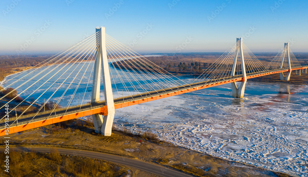 Fototapeta premium Scenic aerial view of cable-stayed bridge over frozen Oka river near Murom city of Vladimir region on sunny winter day, Russia.