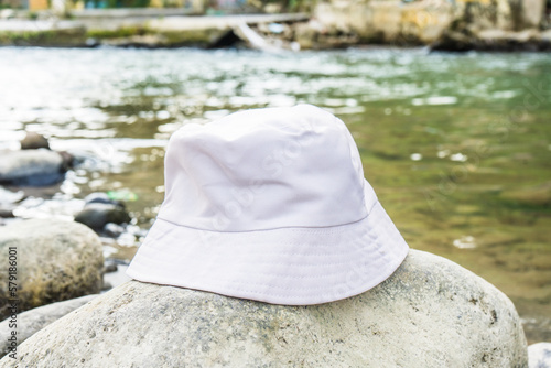 With its pristine white color and tasteful placement above a rock, this bucket hat enhances the overall aesthetic of the tranquil river setting