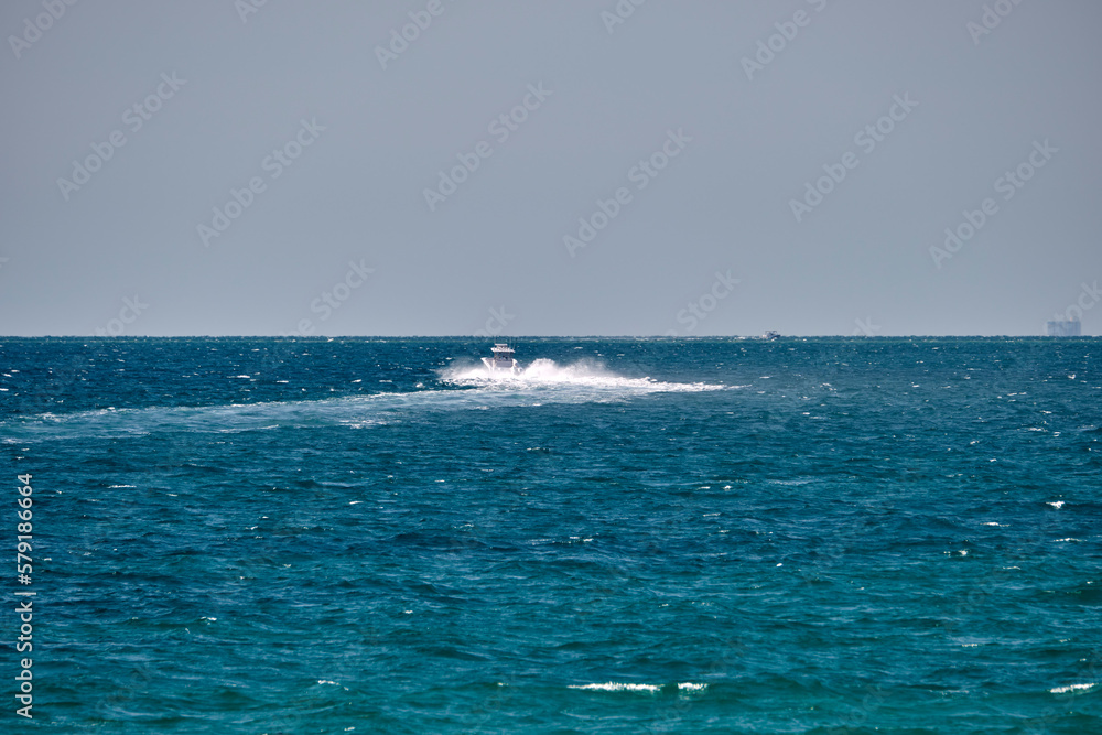 Seascape with ripple surface of blue sea water with white speedboat swimming fast on calm waves Seascape with ripple surface of blue sea water with white speedboat swimming fast on calm waves
