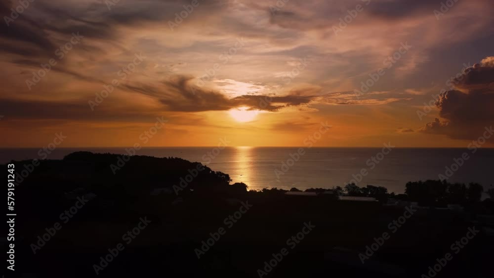 Sunset over sea filmed from rocky coast by drone at warm summer evening. View of mountain silhouette and dusk above ocean. There is sunshine reflection on water surface. Romantic evening on shore Sunset over sea filmed from rocky coast by drone at warm summer evening. View of mountain silhouette and dusk above ocean. There is sunshine reflection on water surface. Romantic evening on shore