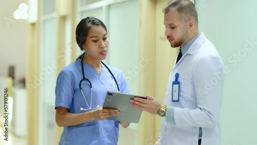 doctor and nurse working in hospital, Caucasian male doctor and Asian female nurse discussing work in hospital Female nurse and male doctor looking at data on tablet