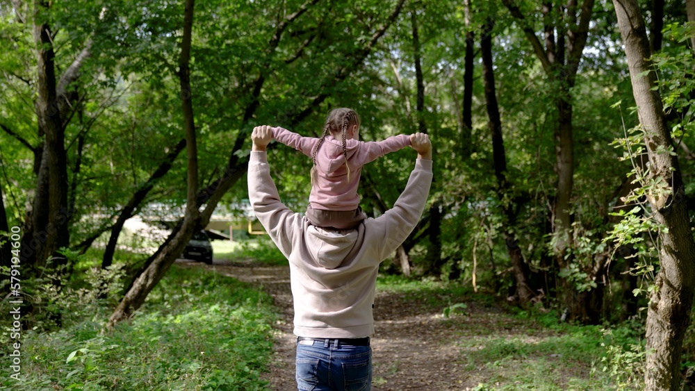 Foto de Happy family, father runs with his daughter on his shoulders in ...