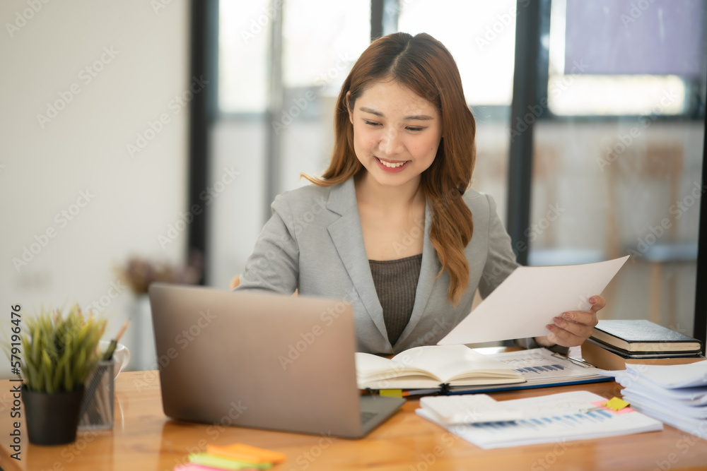 Young Asian businesswoman holding notebook about business, spending money Young Asian businesswoman holding notebook about business, spending money