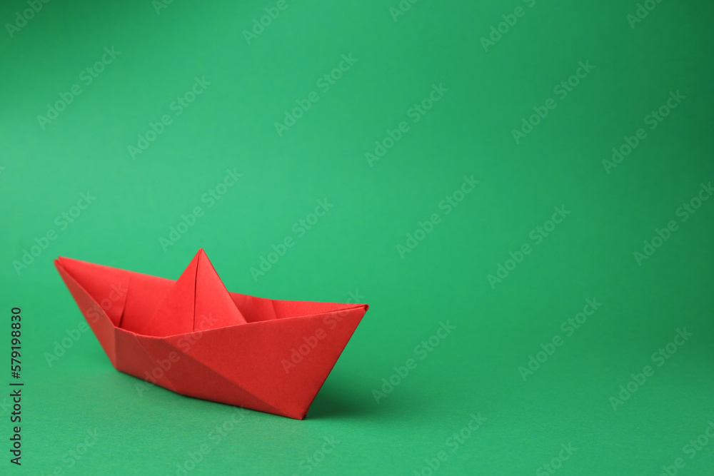 Fototapeta premium Origami art. Paper boat on green background, space for text