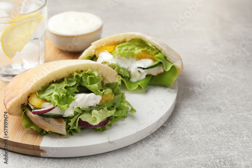Delicious pita sandwiches with chicken breast and vegetables on light gray table, closeup