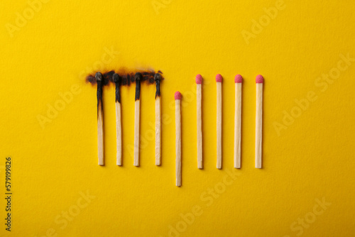 Burnt and whole matches on yellow background  flat lay. Stop destruction by breaking chain reaction concept