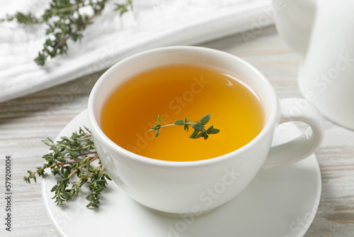 Aromatic herbal tea with thyme on white wooden table, closeup