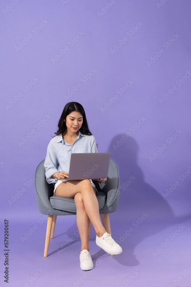 image of girl sitting on sofa isolated on purple background image of girl sitting on sofa isolated on purple background